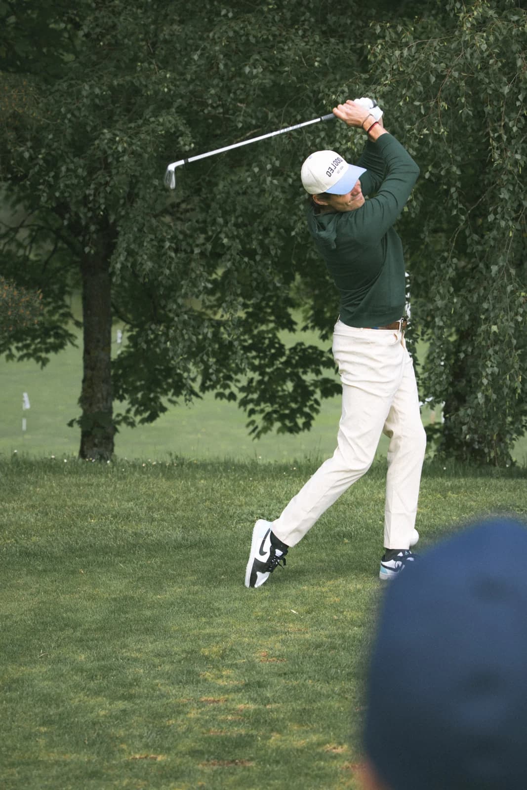 Golfer in green knitwear at the finish of the swing, on an autumn fairway
